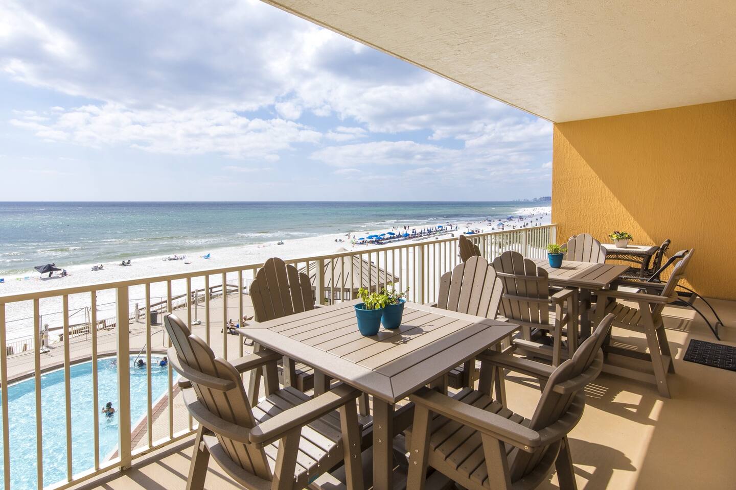 Private Gulf-facing balcony with dining tables and Adirondack chairs